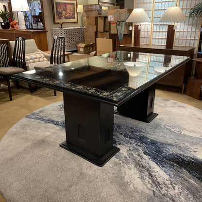 Dining table with black marble top and base in a showroom setting