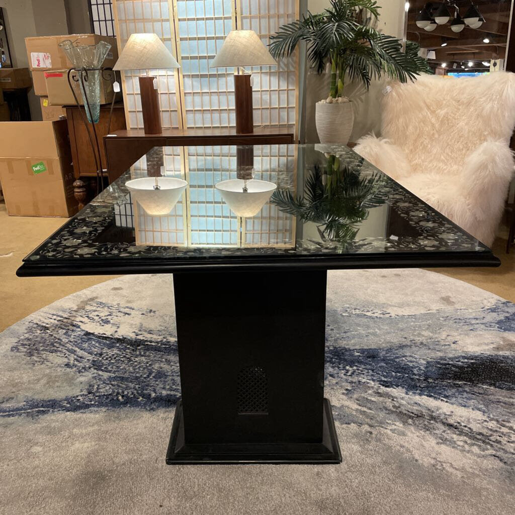 Black marble dining table with a glass top in a room with furniture and decor.