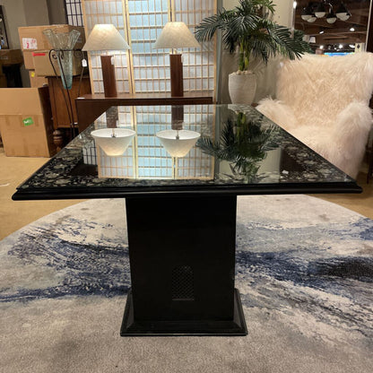 Black marble dining table with a glass top in a room with furniture and decor.