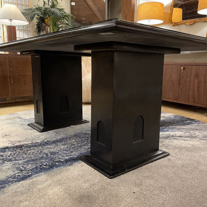 Black corner desk in a room with wooden cabinets and a rug.