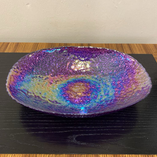 Multicolored glass bowl on a black surface with a wooden edge.