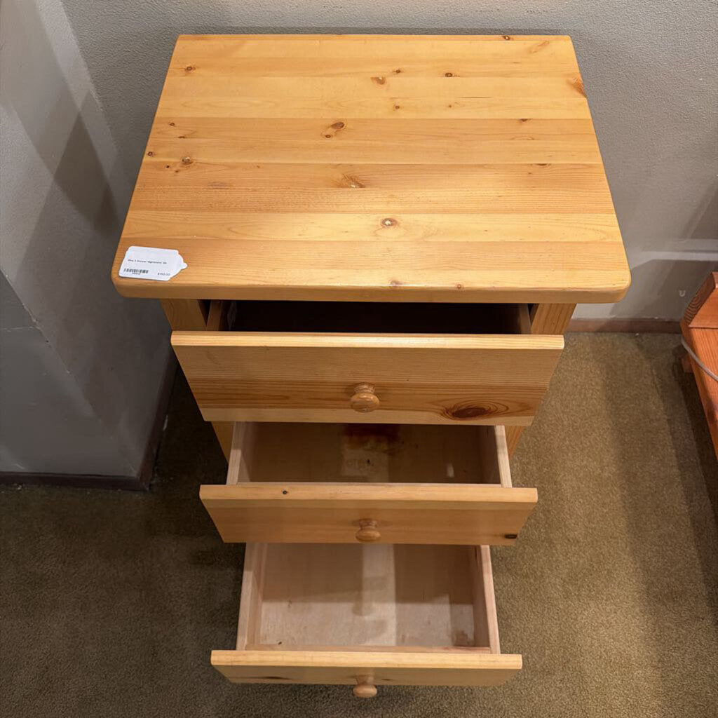 Wooden nightstand with a single drawer open on a carpeted floor.