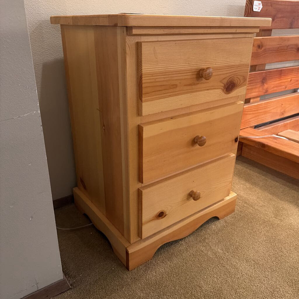 Wooden dresser with three drawers on a carpeted floor.