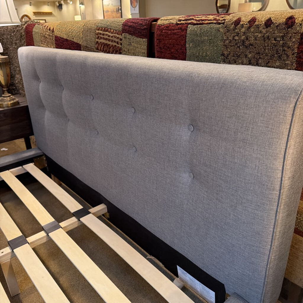 Gray upholstered headboard with tufted design on a bed frame.