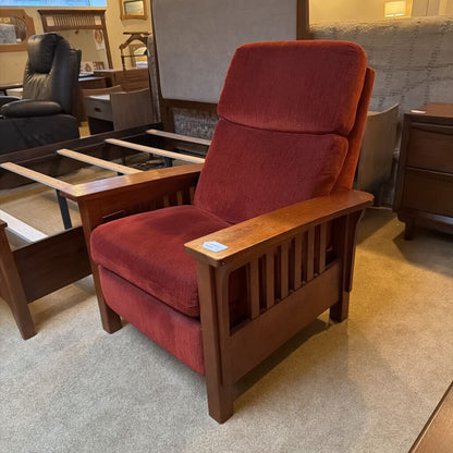 Red recliner chair with wooden frame in a furniture store setting