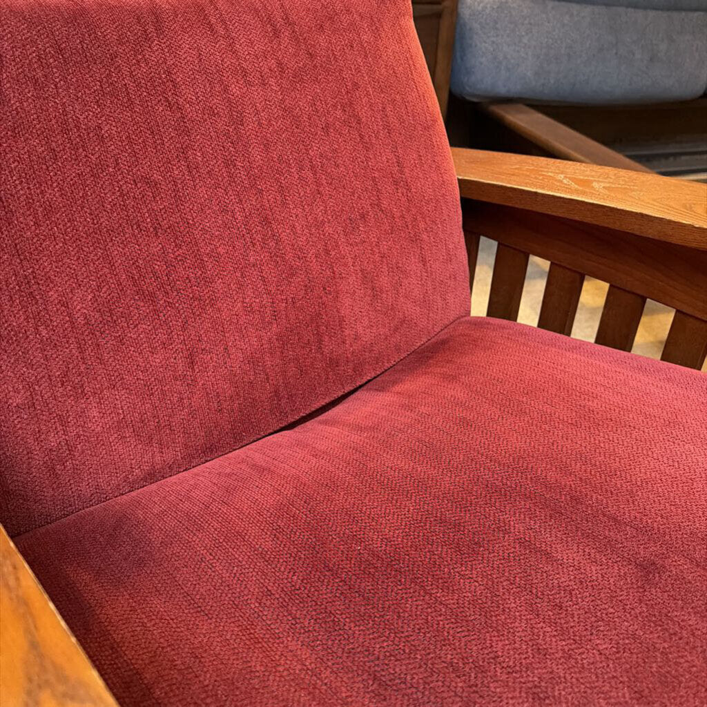 Red upholstered chair with wooden armrests and backrest.