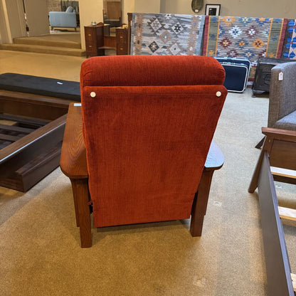 Red upholstered chair in a furniture store setting with other chairs and a rug in the background.