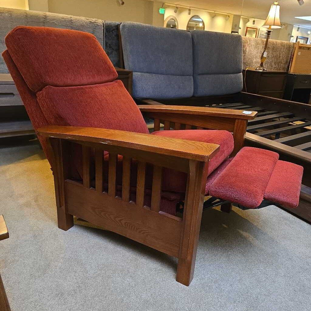 Red recliner chair with wooden frame in a furniture store setting