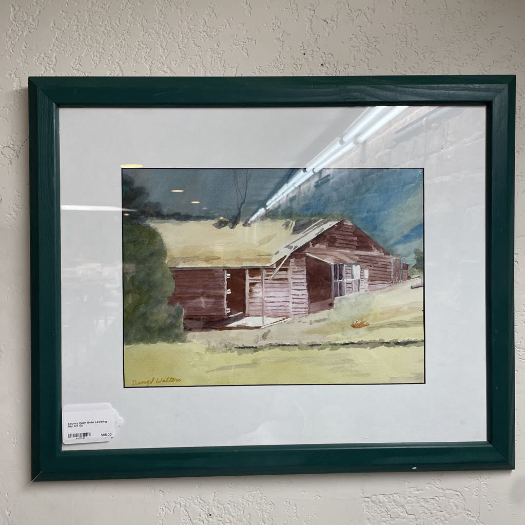 Framed painting of a rustic cabin on a white wall
