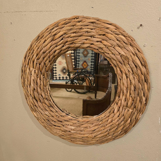 Round woven mirror on a beige wall