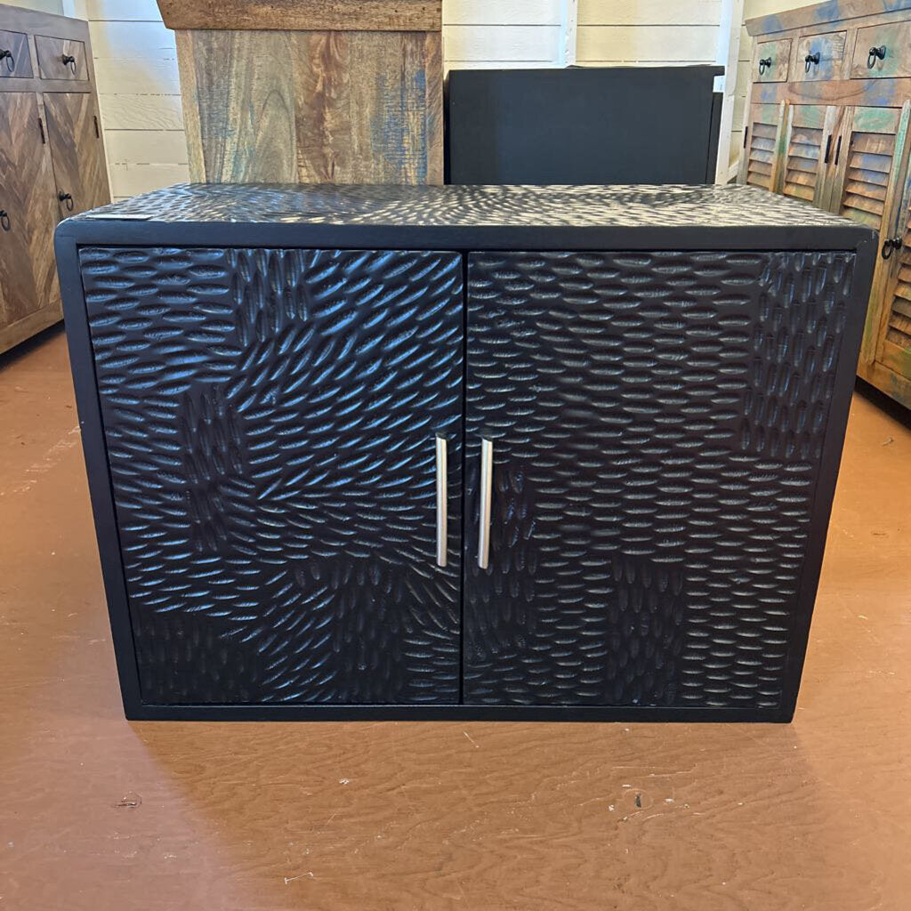 Black textured cabinet with two doors on a wooden floor.