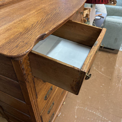 Wooden dresser with an open drawer on a brown floor.