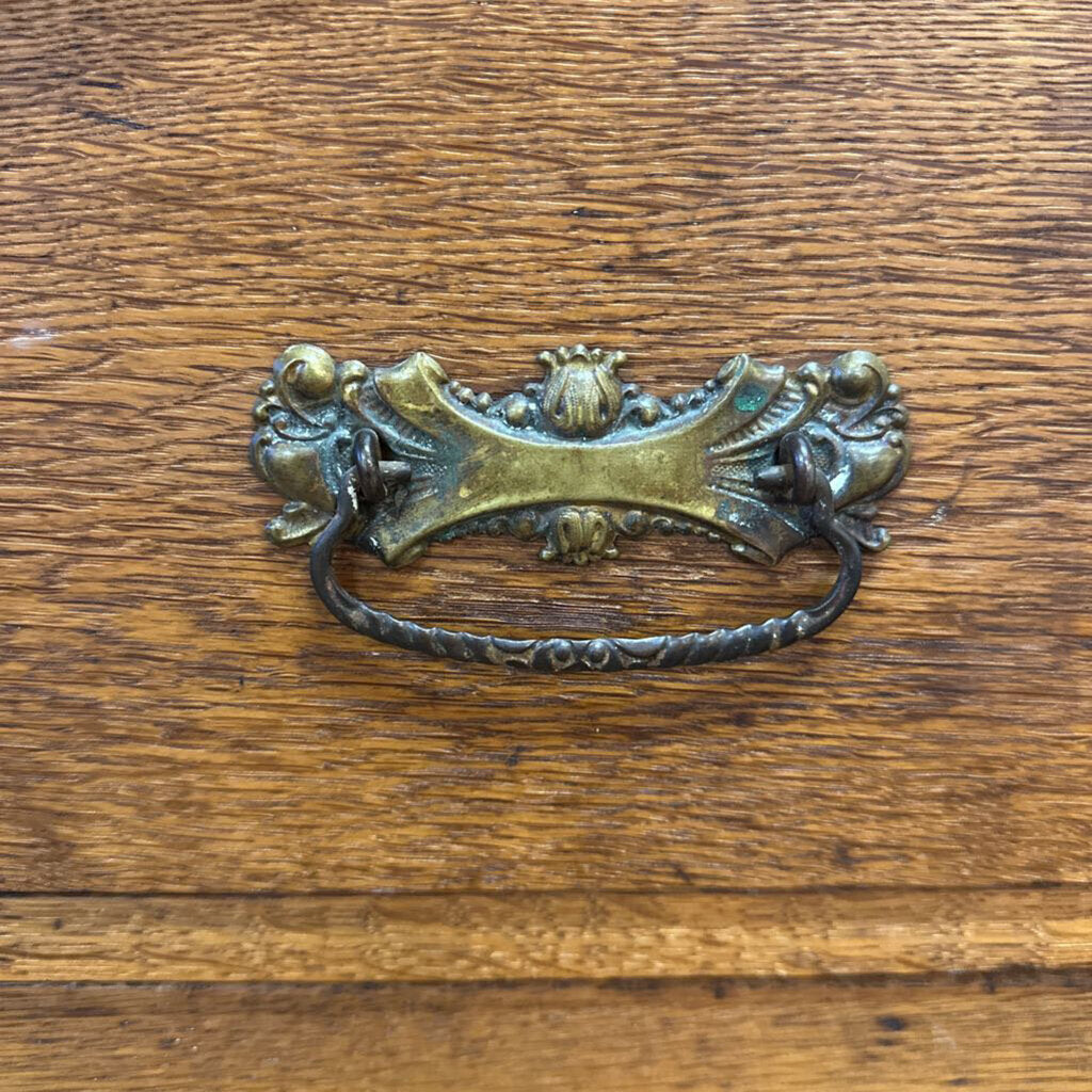 Decorative brass handle on a wooden surface