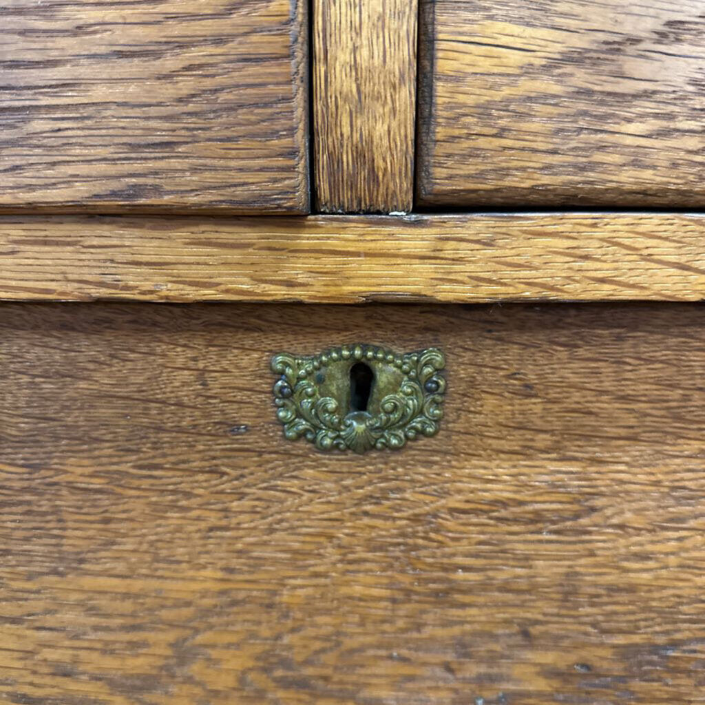 Close-up of a wooden drawer with an ornate metal handle.