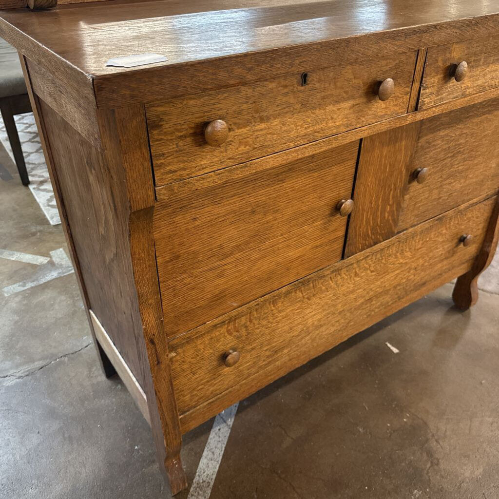 Wooden dresser with multiple drawers on a concrete floor