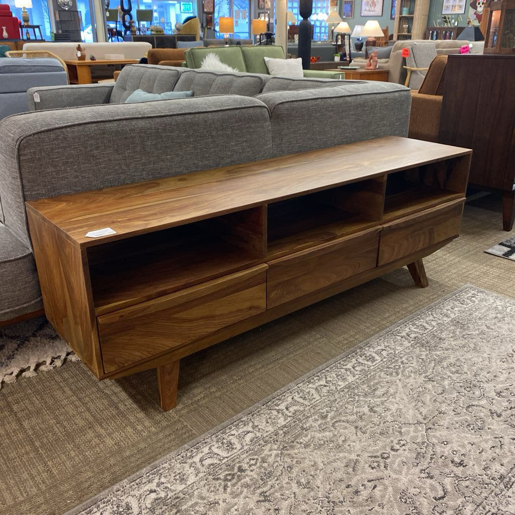 Wooden TV stand in a living room setting with a gray sofa and patterned rug.