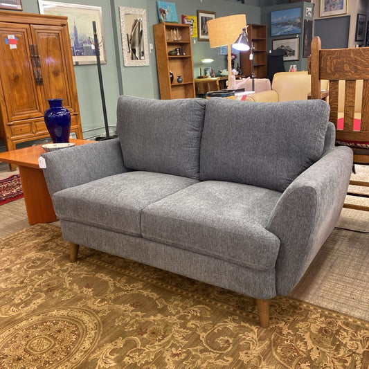 Gray sofa in a furniture store with various items in the background