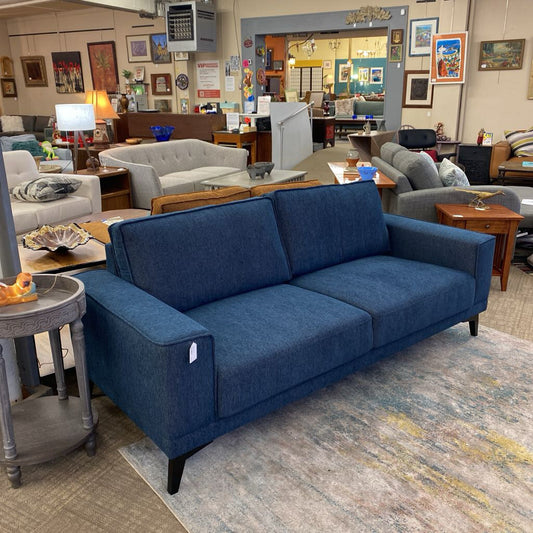 Blue sofa in a furniture store with other couches and decor items.
