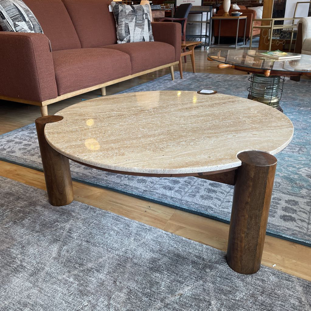 Round marble coffee table with wooden legs in a living room setting