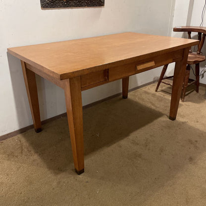 Wooden desk in a room with a chair and wall art.