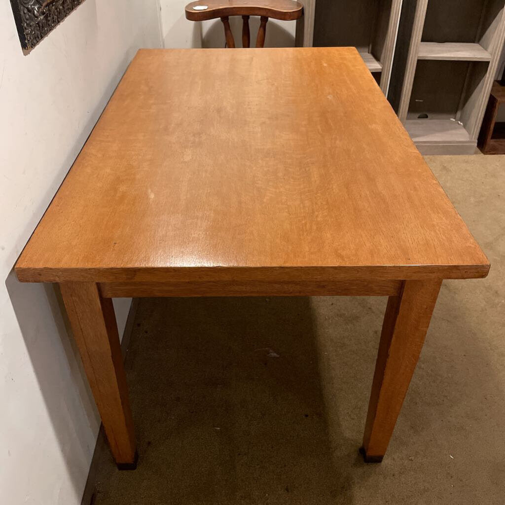 Wooden table in a room with a chair and shelves.