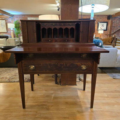 Wooden desk in a living room setting with furniture and decor in the background