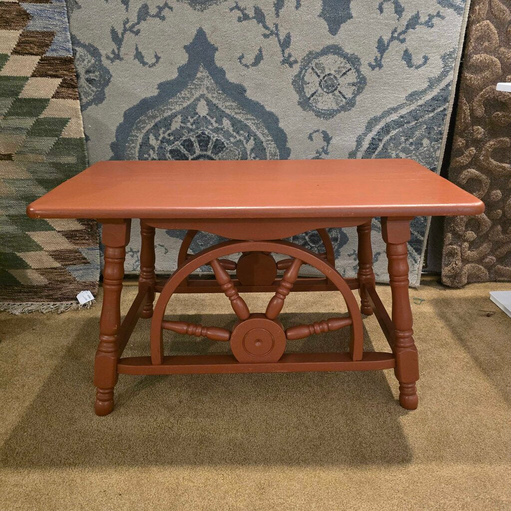 Wooden table with decorative wheel design on a carpeted floor