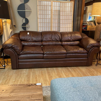 Brown leather sofa in a room with wooden flooring and decorative elements.