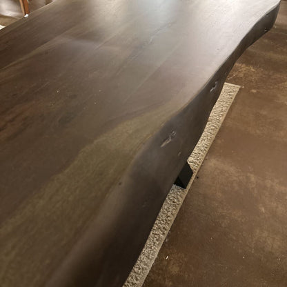 Dark wooden bench with a textured surface on a concrete floor