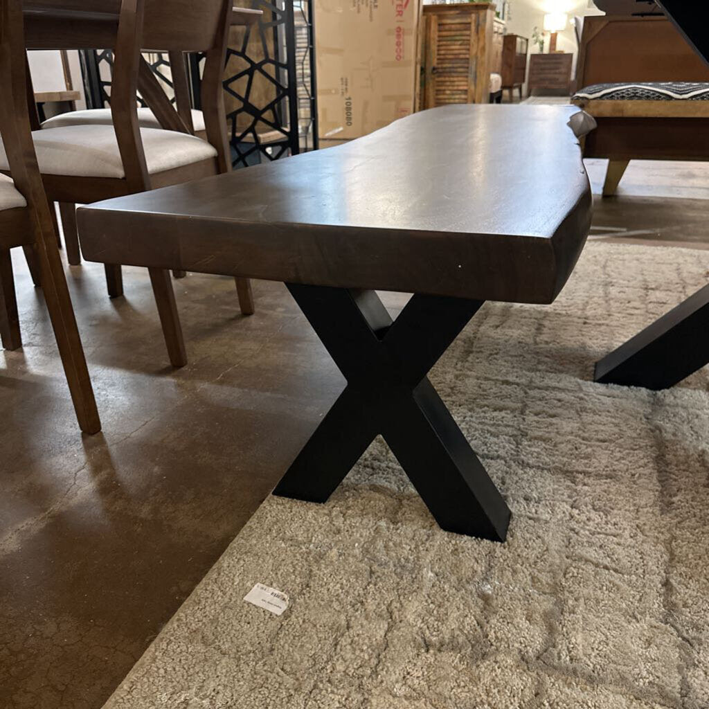 Dark wooden dining table with X-shaped base in a showroom setting