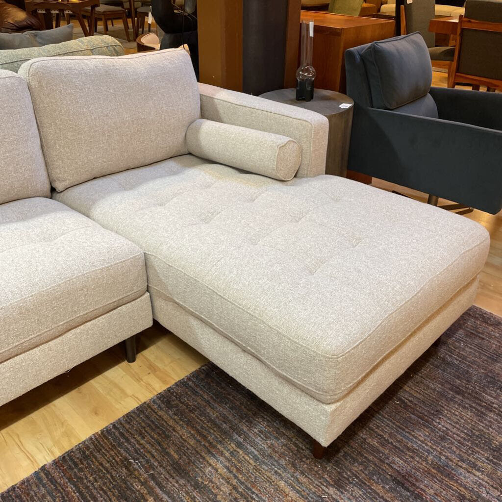 Beige sectional sofa in a showroom setting with other furniture.