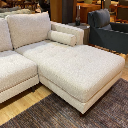 Beige sectional sofa in a showroom setting with other furniture.