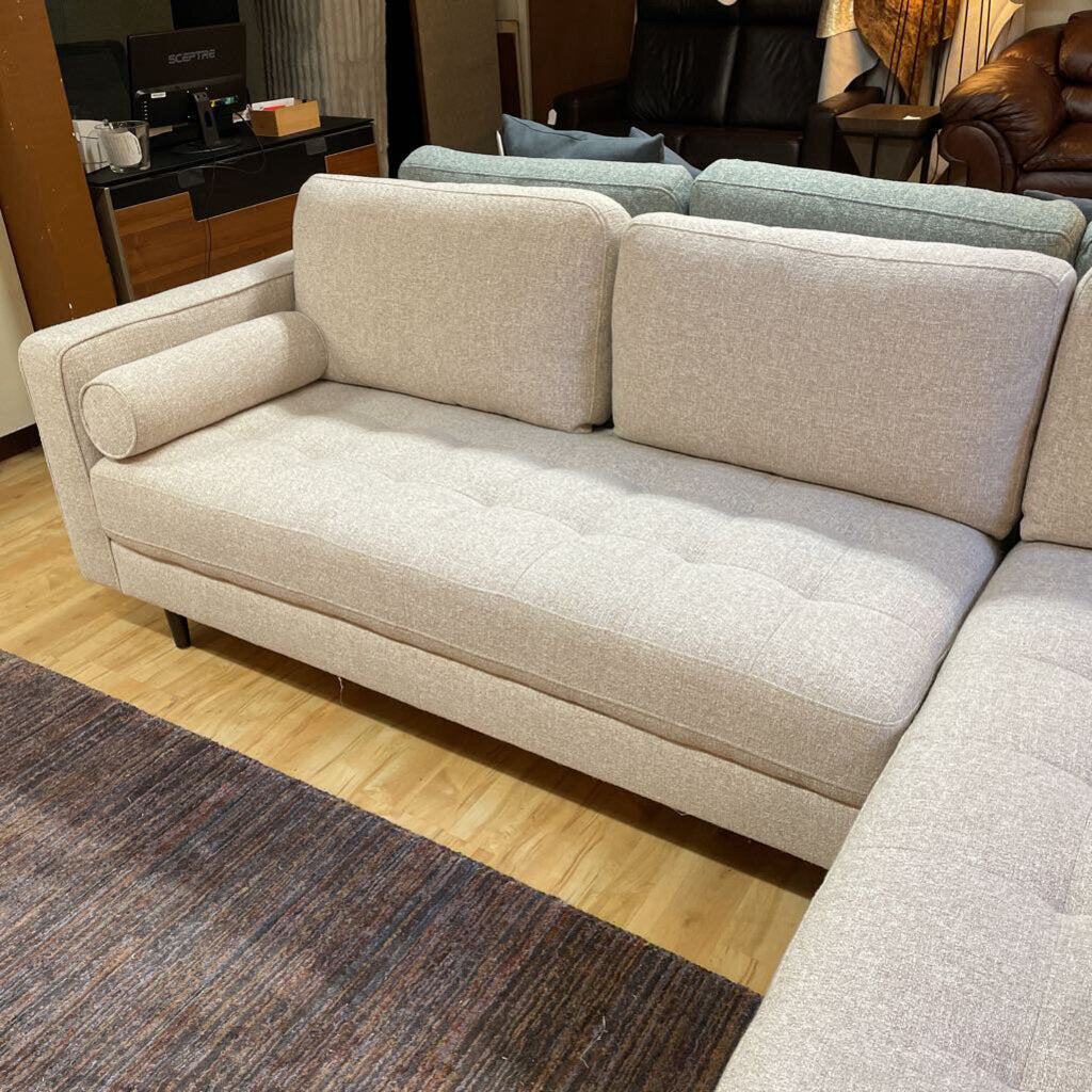 Beige sectional sofa in a living room setting with furniture and decor.