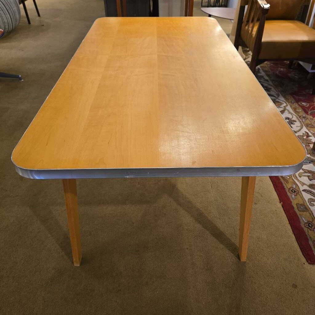 Wooden table with a metal base on a carpeted floor