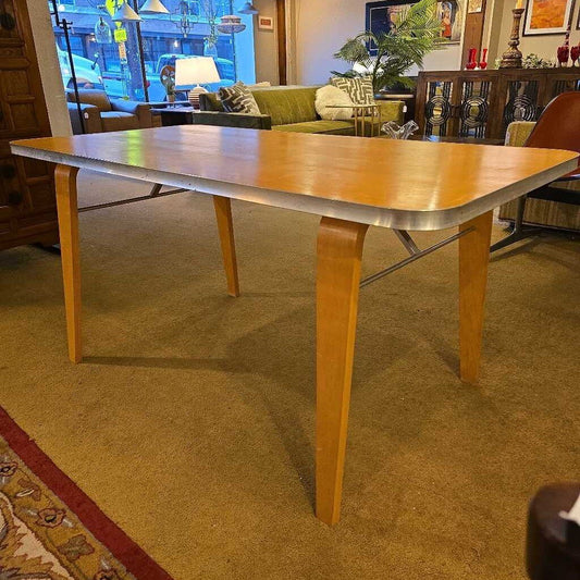 Wooden dining table in a room with a couch and decorative items.