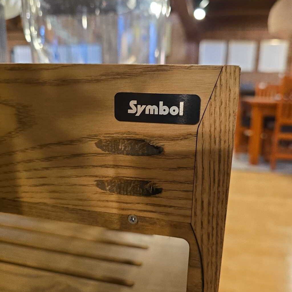 Wooden machine with 'Symbol' logo in a blurred indoor setting