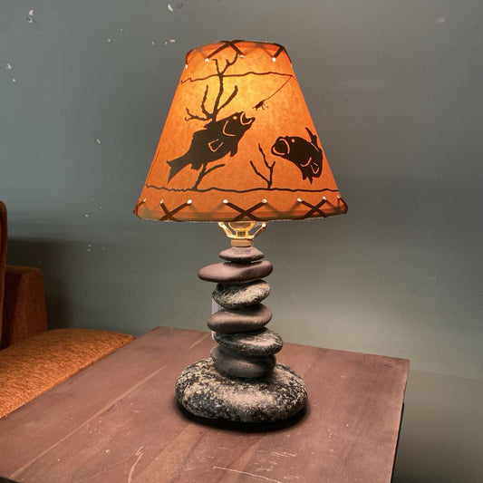 Table lamp with decorative shade and stone base on a wooden surface.
