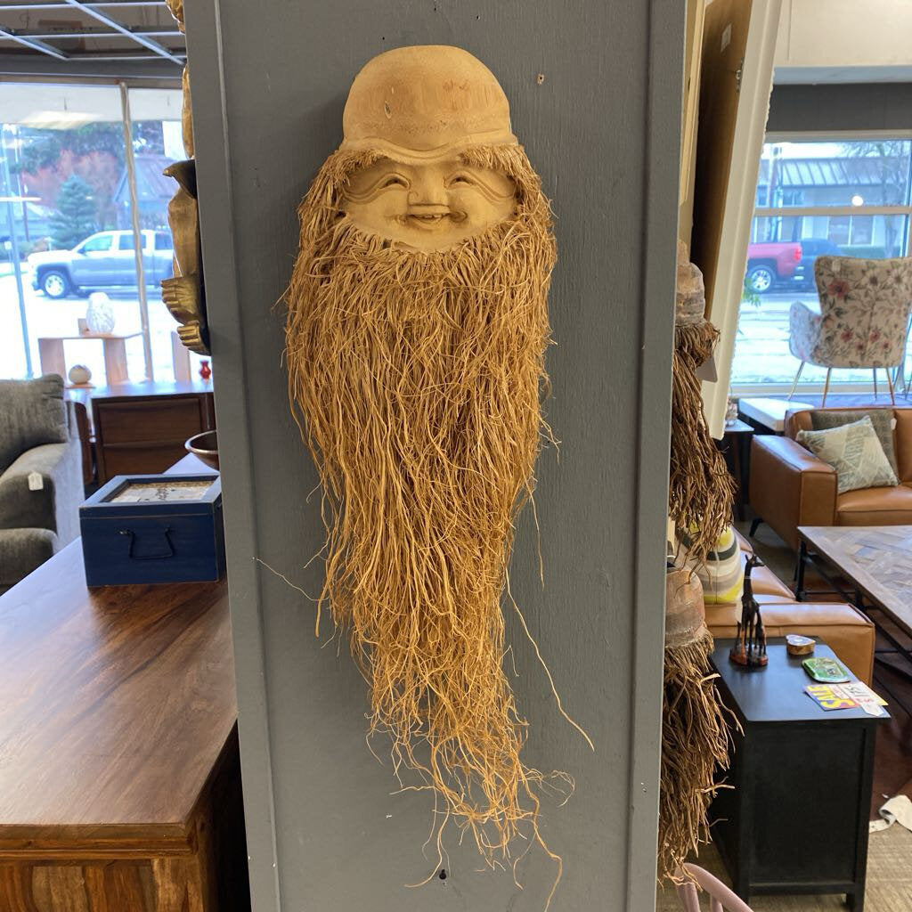 Wooden wall hanging with a face and long beard in a store setting