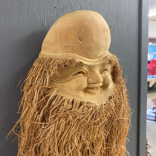 Wooden carving of a face with a beard on a dark background