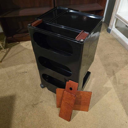 Black metal storage cart with wooden brackets on a carpeted floor.
