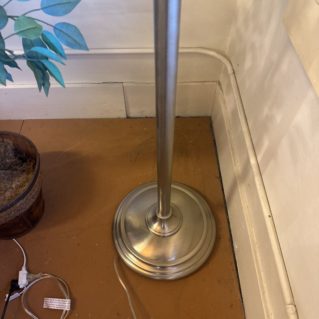 Metal stand on a wooden floor with a plant in the background