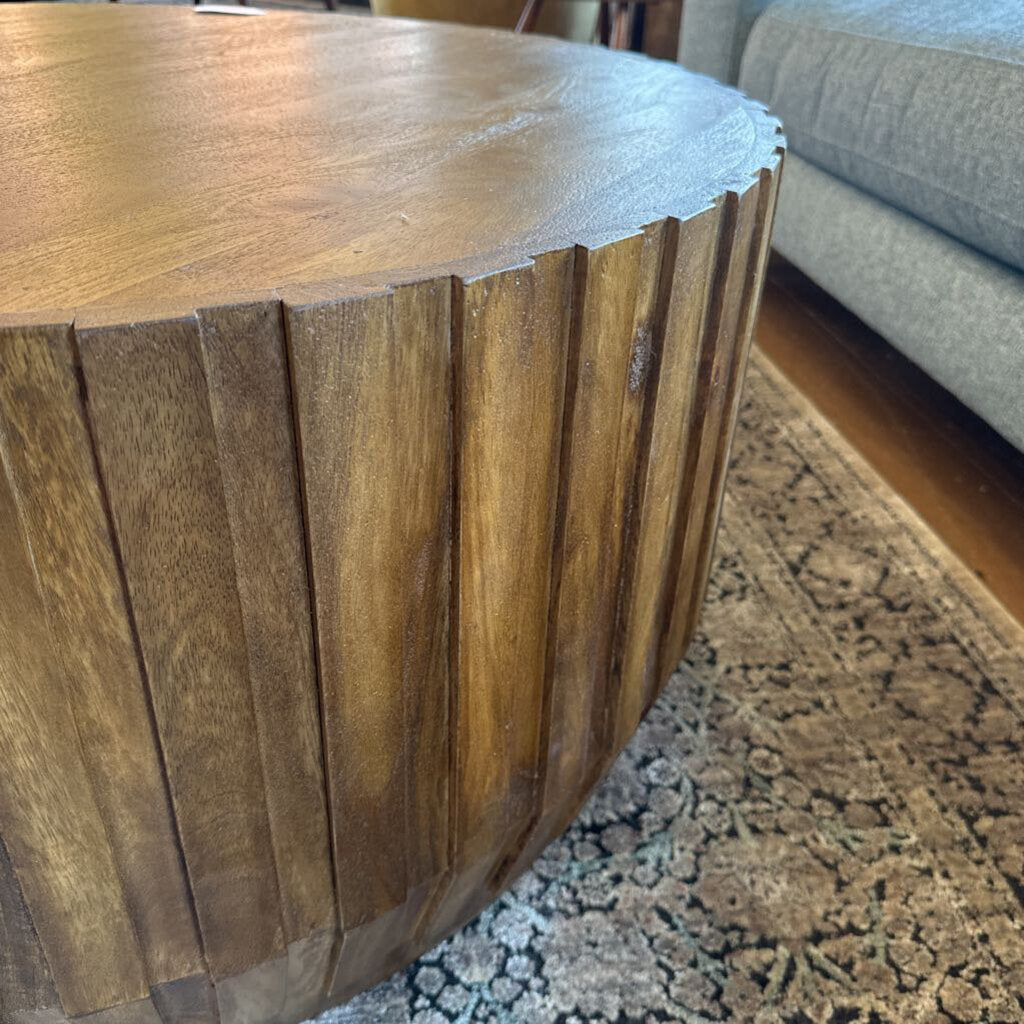 Wooden side table with a textured surface on a patterned rug