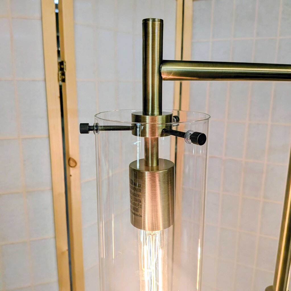Brass and glass shower caddy against a tiled wall