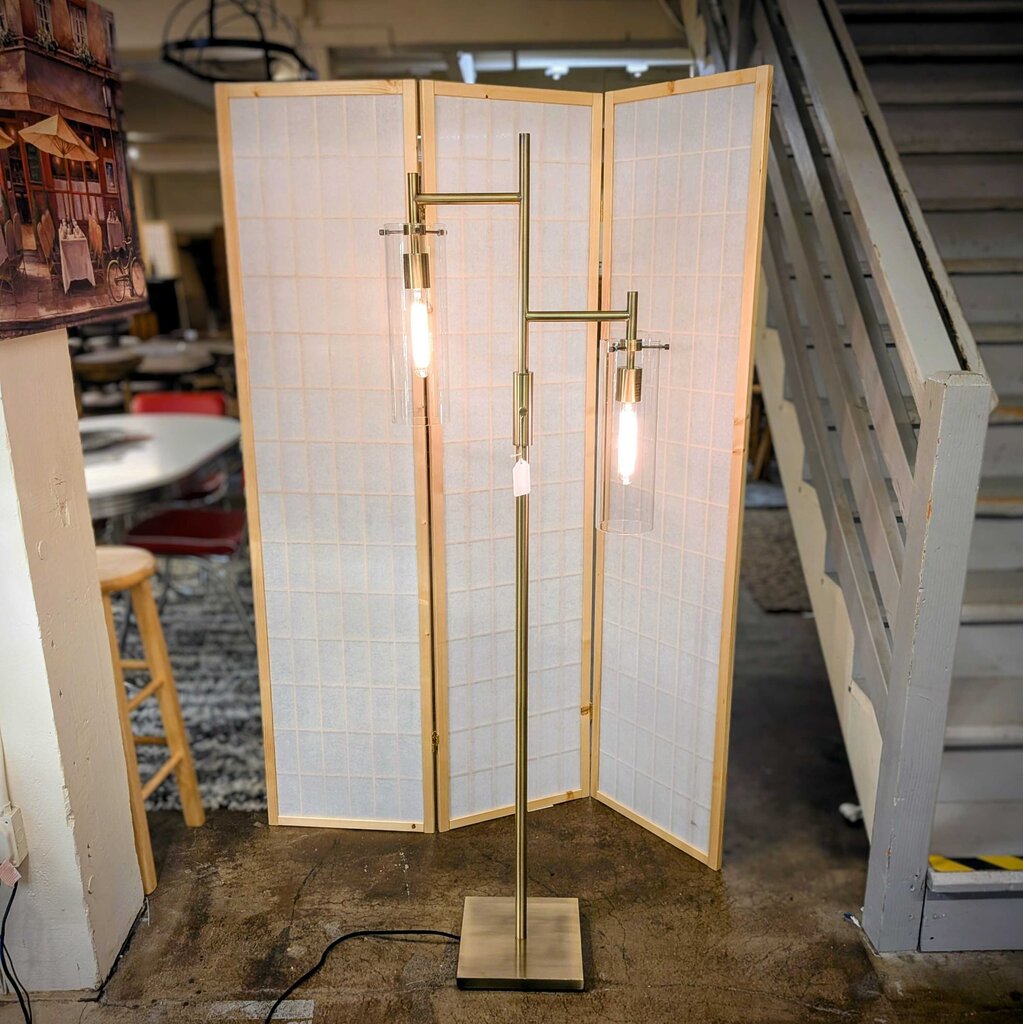 Modern floor lamp with wooden frame and glass panels in a room setting.