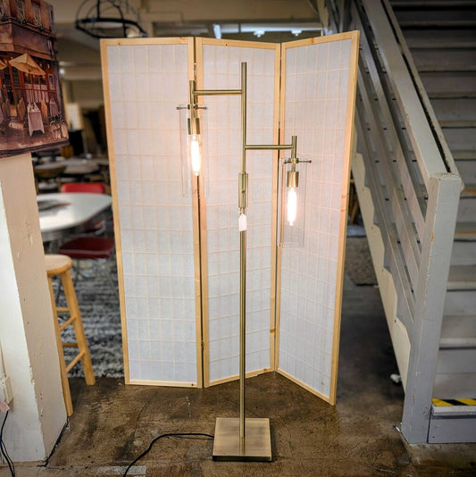 Modern floor lamp with wooden frame and glass panels in a room setting.