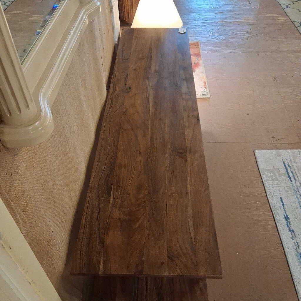 Long wooden board leaning against a wall in a room with carpeted and tiled flooring.