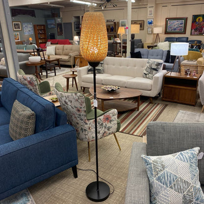 Floor lamp with orange shade in a room with green walls, a plant, and furniture.