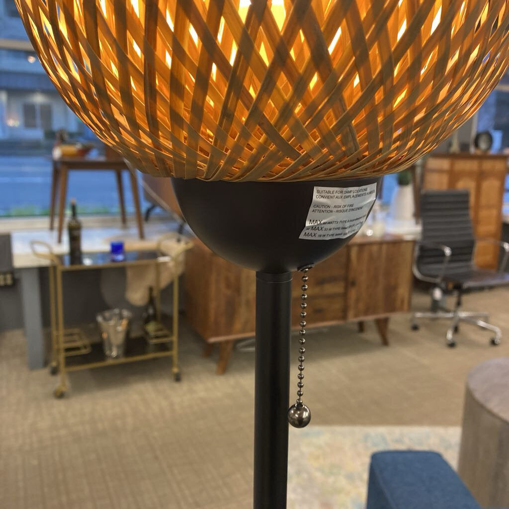 Floor lamp with orange shade in a room with green walls, a plant, and furniture.