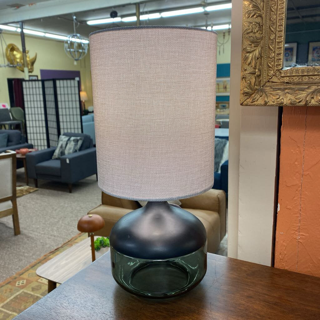 Lamp with a beige shade on a wooden table in an indoor setting