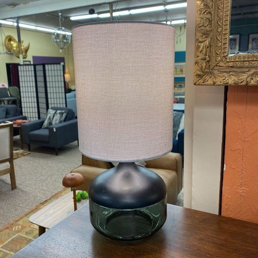 Lamp with a beige shade on a wooden table in an indoor setting